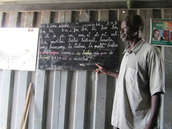 Photo of man pointing to words on a chalkboard.